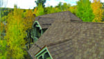 multi-level home featuring a warm brown shingle roof with defined ridgelines