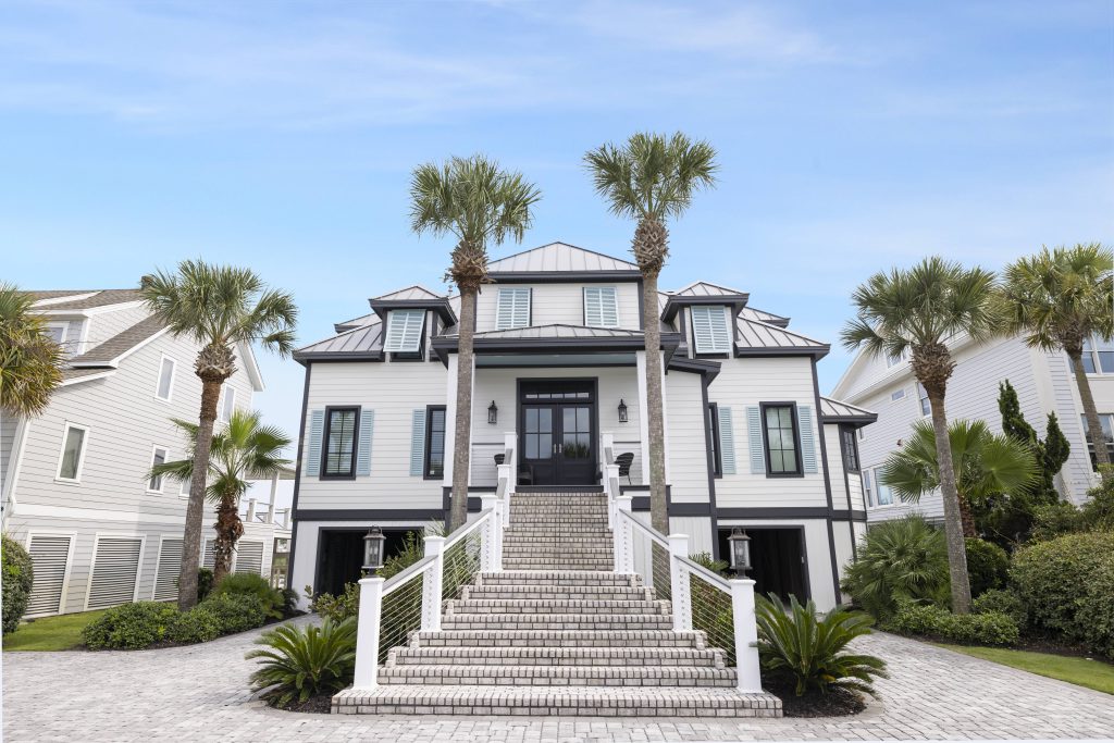 Southern coastal home design featuring crisp white siding, light blue shutters, a durable gray roof, and a grand elevated entryway.
