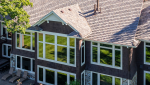 Minnesota home exterior featuring dark siding, stone veneer accents, and a highly durable DaVinci composite shake roof replacement.