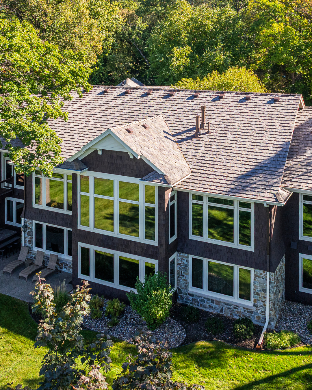 Minnesota home exterior featuring dark siding, stone veneer accents, and a highly durable DaVinci composite shake roof replacement.
