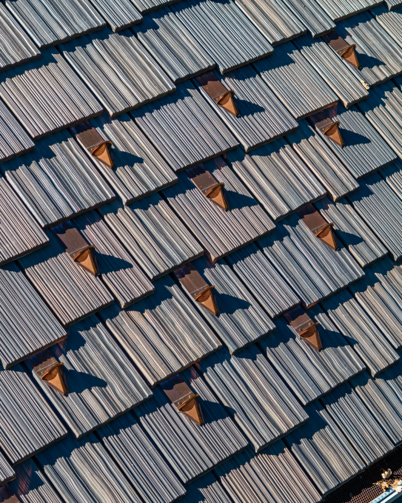 Close-up of DaVinci composite shake roofing tiles in an Aged Cedar blend, featuring authentic wood texture and installed snow guards.