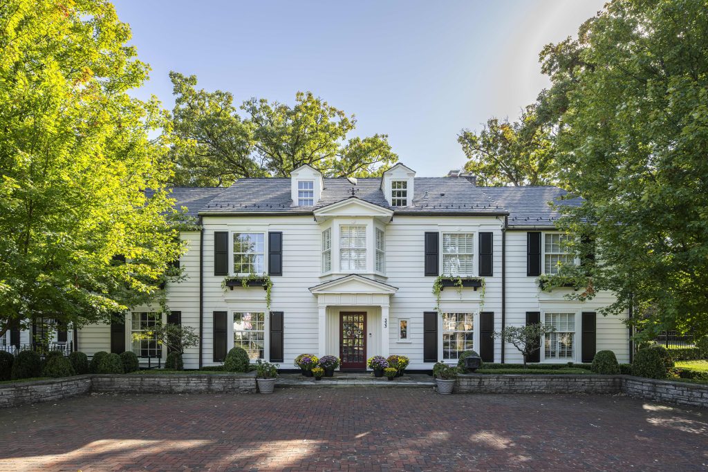 Home exterior featuring white clapboard siding, symmetrical black shutters, and a welcoming dark red front door.