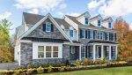 Traditional home exterior showcasing regional design trends with a blend of white horizontal siding, rugged dark stone veneer, and classic black shutters.