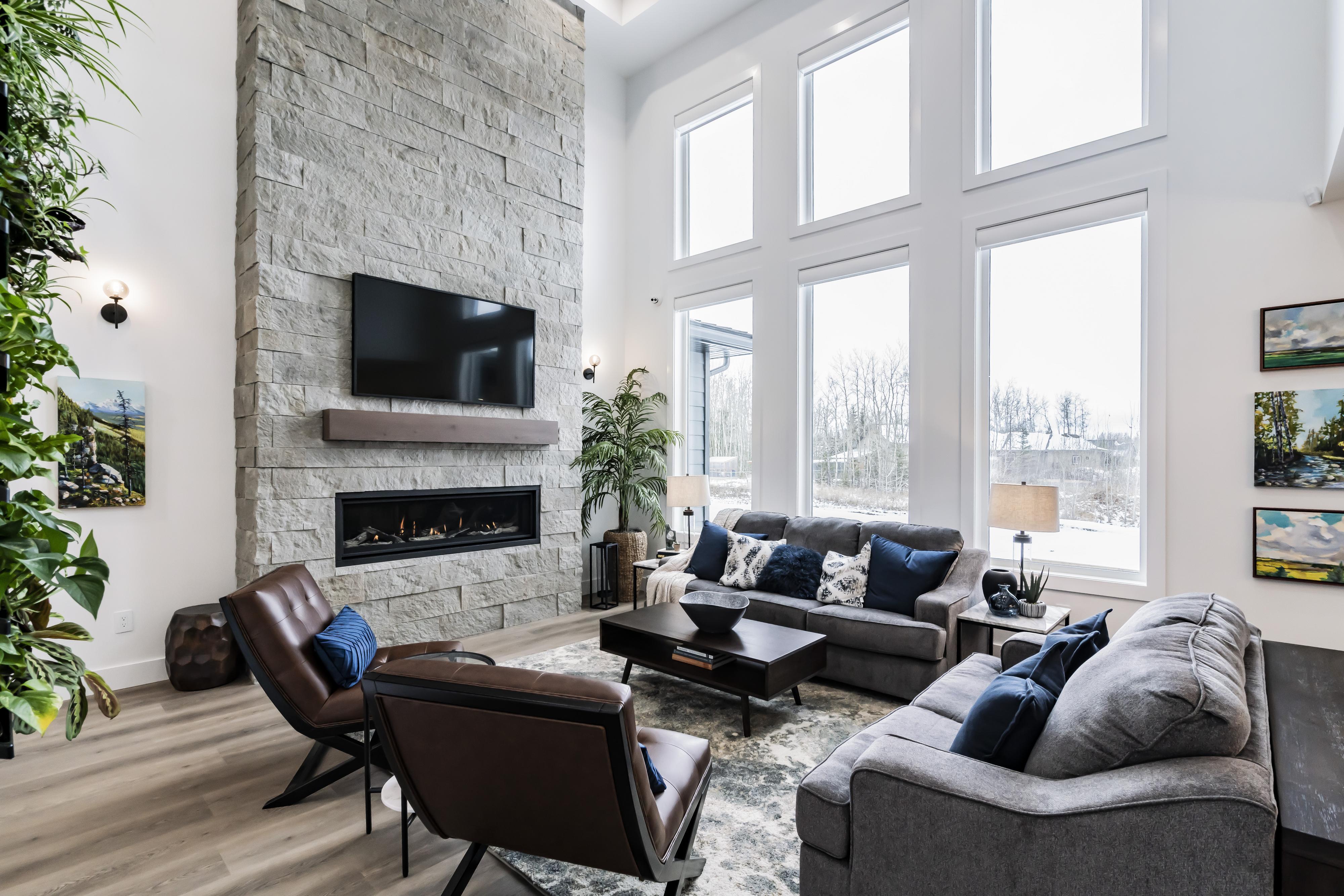 Living room with stone fireplace, large windows, and furniture.