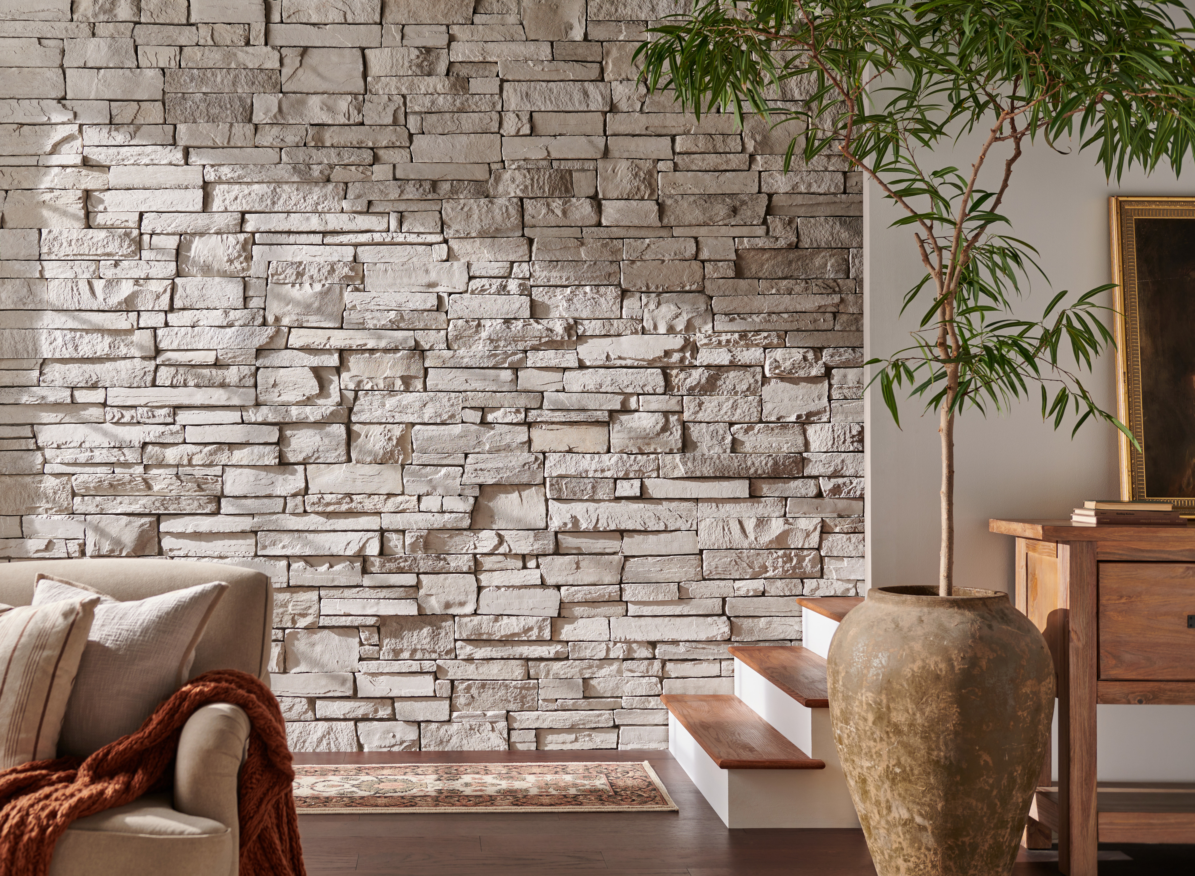 Stone accent wall with a plant and furniture.