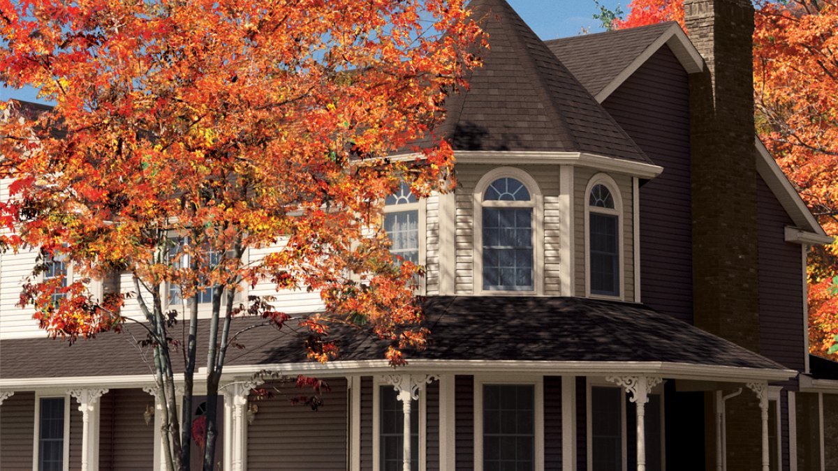 Historic home with a white wrap around porch and fall foliage