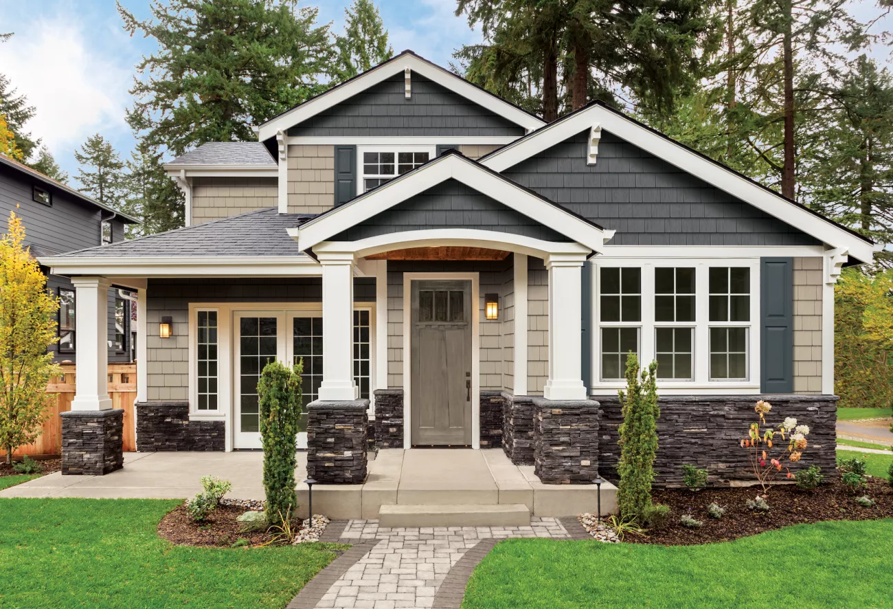 two-toned rustic home with grey stone accents and large windows with grey shutters